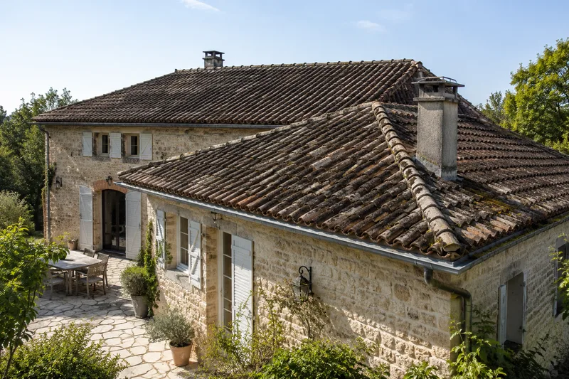 Ferme en pierre à toiture ancienne, tuiles patinées et moussues (illustration générée par IA)